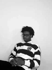 Portrait en noir et blanc de Alain, assis en pull rayé