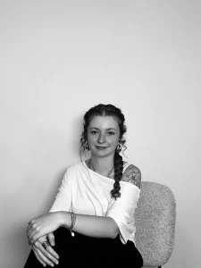 Portrait en noir et blanc de Paloma, assise et souriante en haut blanc
